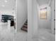 Hallway with a staircase and view to the kitchen featuring stylish marble floors and neutral decor at 10549 Torchwood Sea Way, San Antonio, FL 33576