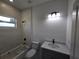 Bathroom with tiled tub, white walls, toilet, gray cabinets, and speckled countertop at 2346 Logsdon St, North Port, FL 34287