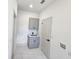 Laundry room with gray cabinets, sink, and white tile floors at 2346 Logsdon St, North Port, FL 34287