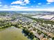 Aerial view showcasing a community near a large commercial building and a lake, surrounded by trees and clear skies at 12511 Lake Vista Dr, Gibsonton, FL 33534