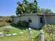 A home's exterior with a ladder is displayed surrounded by a grassy yard with a table and foliage at 316 Country Club Dr, Oldsmar, FL 34677