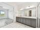 Bright bathroom with gray cabinets, double sinks, marble countertop, and tile flooring at 8936 Sanders Tree Loop, Wesley Chapel, FL 33545