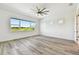 Bright bedroom featuring wood-look floors, a ceiling fan, and a large window providing natural light and a picturesque view at 8936 Sanders Tree Loop, Wesley Chapel, FL 33545
