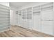 Large walk-in closet with custom shelving and wood-look floors at 8936 Sanders Tree Loop, Wesley Chapel, FL 33545