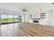 A modern living room featuring a stone fireplace, floating shelves, wood-look flooring and a large glass sliding door at 8936 Sanders Tree Loop, Wesley Chapel, FL 33545