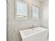 Glass-enclosed shower with modern fixtures, marble-style tile, and natural light from a nearby window at 8936 Sanders Tree Loop, Wesley Chapel, FL 33545