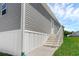 The exterior of the home features gray siding, a white staircase, and green grass at 8857 Highpoint Blvd, Brooksville, FL 34613