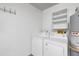 Bright laundry room features a newer washer, dryer, water heater, and functional storage shelving at 754 Cape Cod Cir, Valrico, FL 33594