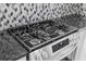 Close-up of gas cooktop oven with stainless steel finish and elegant backsplash at 754 Cape Cod Cir, Valrico, FL 33594