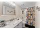 Well-lit bathroom featuring a marble-top vanity, decorative mirror, and shower-tub combo with a vibrant curtain at 3035 Countryside Blvd # 15B, Clearwater, FL 33761