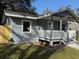 A quaint home featuring a covered front porch, grey siding, and freshly landscaped yard at 8306 N Orleans Ave, Tampa, FL 33604