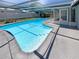 Beautiful in-ground pool with clear blue water, surrounded by a screened enclosure and spacious patio area at 9210 Crabtree Ln, Port Richey, FL 34668
