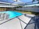 Screened-in pool with clear blue water, surrounded by a spacious deck and lush green yard at 9210 Crabtree Ln, Port Richey, FL 34668