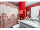Bathroom with a colorful shower curtain, a gray vanity with a marble countertop and a red accent wall at 2248 Bonn Ct, Punta Gorda, FL 33983