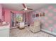 Bright Bedroom featuring a ceiling fan, a plush chair, polka dot wall decor, and gray wood-look flooring at 2248 Bonn Ct, Punta Gorda, FL 33983