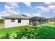 A beautiful backyard with a screened-in pool, lush green grass, and solar panels on the roof at 2248 Bonn Ct, Punta Gorda, FL 33983