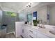 Modern bathroom with dual sinks, white cabinetry, frameless shower, and a large mirror at 2366 Wise River Lane, Zephyrhills, FL 33539