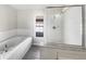 Bright bathroom featuring a soaking tub and glass-enclosed shower, tiled floors, and a window for natural light at 30406 Arrochar St, Wesley Chapel, FL 33545