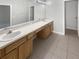 Bathroom vanity showcasing double sinks, spacious countertop, wooden cabinetry, tile floor, and a large mirror at 30406 Arrochar St, Wesley Chapel, FL 33545