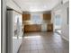 Bright kitchen featuring tile flooring, wood cabinets, and modern appliances, including a white refrigerator at 30406 Arrochar St, Wesley Chapel, FL 33545