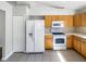 This open kitchen features white appliances, wood cabinets, tile floors and plenty of natural light at 30406 Arrochar St, Wesley Chapel, FL 33545
