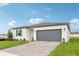 Charming single-story home with a paved driveway, well-maintained lawn, and a gray two-car garage door at 1752 Brekey Way, Zephyrhills, FL 33541