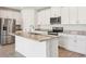 Modern kitchen with stainless steel appliances, granite countertops, and white cabinets and an island sink at 1752 Brekey Way, Zephyrhills, FL 33541