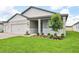 Landscaped front yard of a charming gray home with well-manicured lawn and blue shutters at 1787 Draughton Dr, Zephyrhills, FL 33541