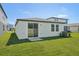 Spacious backyard with green lawn, slider door, and view of the home's rear exterior at 1861 Brekey Way, Zephyrhills, FL 33541