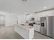 Bright, open-concept kitchen featuring white cabinets, stainless steel appliances, and a large island with granite countertops at 1861 Brekey Way, Zephyrhills, FL 33541
