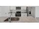 Modern kitchen featuring white cabinets, stainless steel appliances, a granite countertop, and a stainless steel sink at 1861 Brekey Way, Zephyrhills, FL 33541