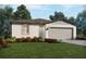 Charming single-story home featuring a two-car garage, manicured lawn and colorful flower beds at 31596 Wild Grape Ln, Brooksville, FL 34602