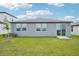 Home backyard featuring green grass, a patio area, and sliding glass doors at 31643 Wild Grape Ln, Brooksville, FL 34602