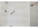 The bright white tiled shower features a shower head and grab bar for safety and ease at 3206 Peterborough St, Holiday, FL 34690