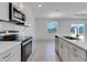 Modern kitchen with stainless steel appliances, white cabinets, and an island with a sink at 10008 Last Light Gln, Parrish, FL 34219