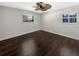 Empty bedroom with dark wood floors, neutral walls, and natural light from two windows at 4825 W Bay Court Ave, Tampa, FL 33611