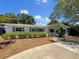 Charming single-story home featuring a well-manicured lawn, beautiful landscaping, and a concrete driveway at 4825 W Bay Court Ave, Tampa, FL 33611