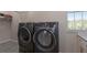 Well-equipped laundry room featuring gray washer and dryer with tile floor and a storage shelf at 8035 St Simons St # 8035, University Park, FL 34201