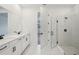 Modern bathroom with double sinks, white cabinets, glass-enclosed shower, and view into bedroom at 14035 Kelly Park Ct, Parrish, FL 34219