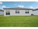 Spacious backyard featuring lush green grass and a modern home exterior at 7736 Gilchrist Springs Dr, Parrish, FL 34219