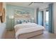 Relax in this stylish bedroom featuring cool color accents, a serene painting, and a private balcony with an outdoor view at 17378 Alderwood Ln, Punta Gorda, FL 33982