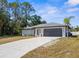 This single-story home boasts a spacious driveway, a gray roof, and mature landscaping at 4284 Persian Ln, North Port, FL 34287