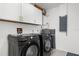 A laundry room featuring modern Samsung washer and dryer set with white cabinets and gold hardware at 4284 Persian Ln, North Port, FL 34287