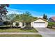 Charming single-story home featuring a well-manicured lawn and a classic white garage door at 6731 Northlake Dr, Zephyrhills, FL 33542