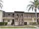 Condo with beige exterior, brown trim, two stories, and a mature palm tree in front at 8440 Old Post Rd # 202, Port Richey, FL 34668