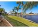 Waterfront backyard featuring a boat dock, lush landscaping, and a serene canal view under a clear blue sky at 9277 St Paul Dr, Port Charlotte, FL 33981
