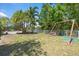 Lush backyard with a playset, mature trees and partial view of the pool and privacy fence at 5474 Dominica Cir, Sarasota, FL 34233