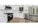 Modern kitchen with white cabinets, stainless steel appliances, and wood-look flooring at 4925 Alcazar S Way, St Petersburg, FL 33712