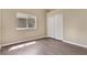 Simple bedroom featuring wood floors, a bright window, and white closet doors at 12219 Hunters Lake Dr, New Port Richey, FL 34654