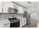 Well-equipped kitchen featuring stainless steel appliances, white cabinets, and mosaic backsplash at 1820 Marvy Ave, Tampa, FL 33612